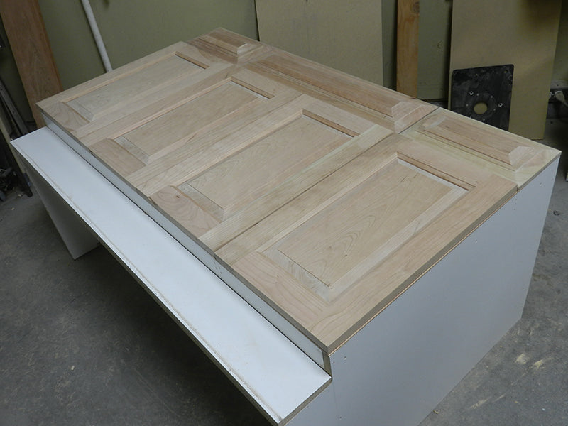 Four bathroom cabinet raised panel doors and drawer panels laid out on top of the original carcass.