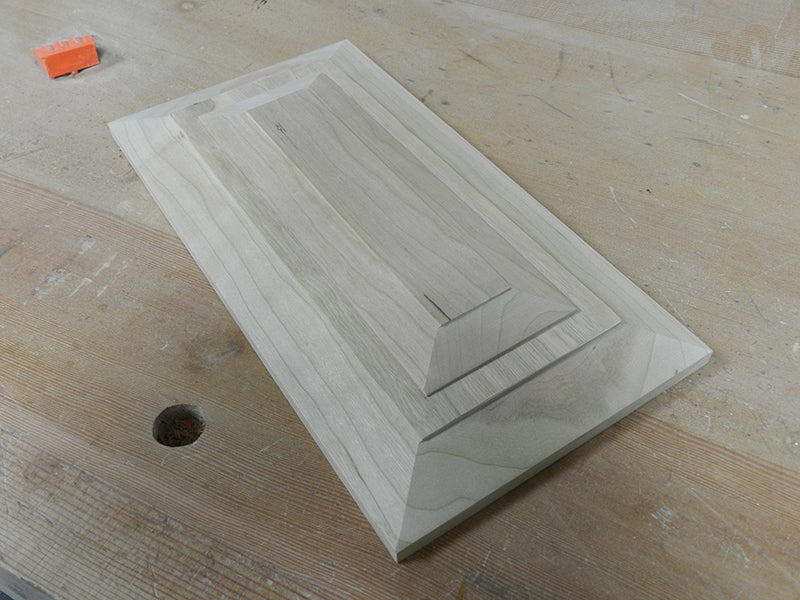 Cabinet drawer bevelled fascia with decorative plate attached.