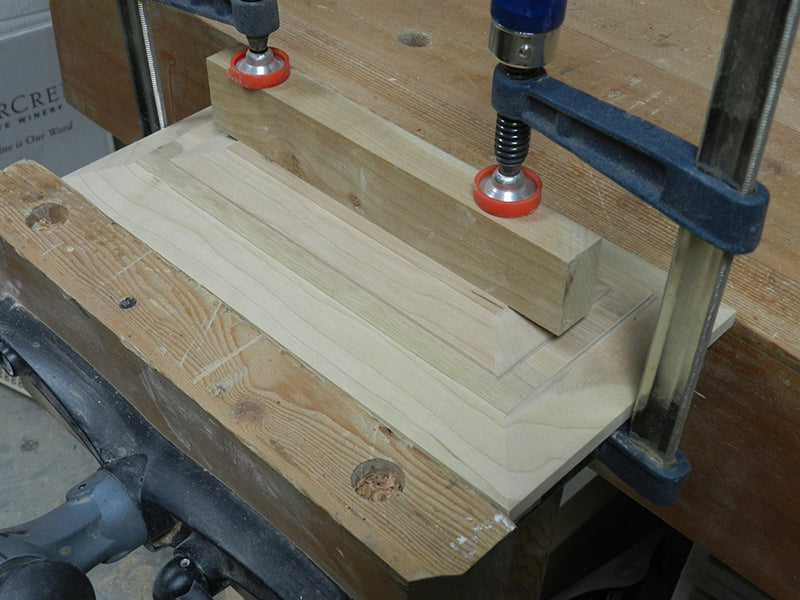 Decorative plate clamped to cabinet drawer beveled fascia work piece.