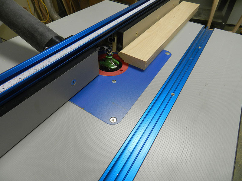 Routing the profile on one of the rails used to build the entryway table frame assembly perimeter section using a table mounted router