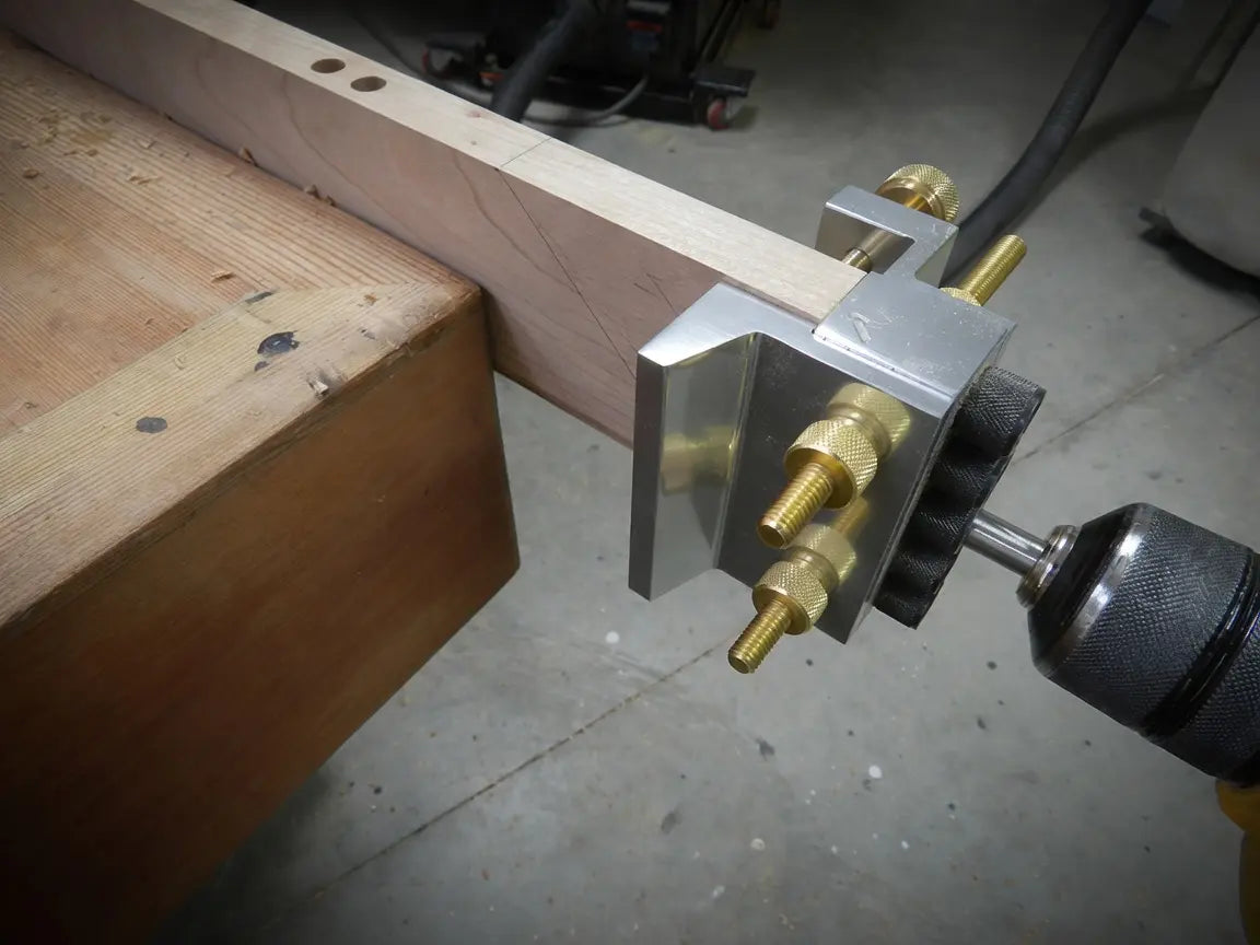 The Dowelmax Classic clamped to a hardwood rail while a drill enters the guide and a row of dowel bores is visible